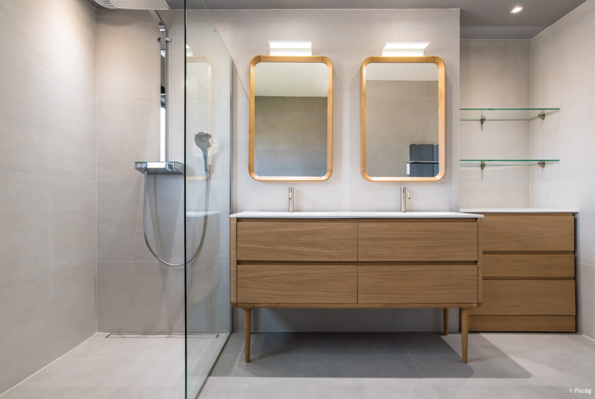 Idée déco salle de bain nature scandinave, meuble double vasque bois chêne naturel sur pieds bois, double miroir rectangulaire cadre bois LED rétroéclairé, robinetterie inox brossé doré, paroi douche verre transparent, pommeau carré inox, étagères verre, carrelage sol béton ciré gris, carrelage mural blanc grand format